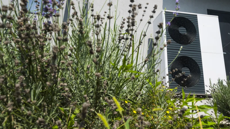 Außen-Wärmepumpe an einem Haus mit Lavendel im Garten